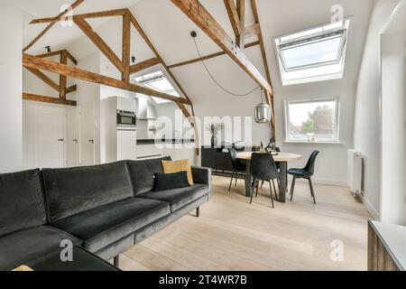 un salon avec poutres en bois au plafond et canapé en cuir noir dans la chambre est bien éclairé par la lumière du soleil Banque D'Images