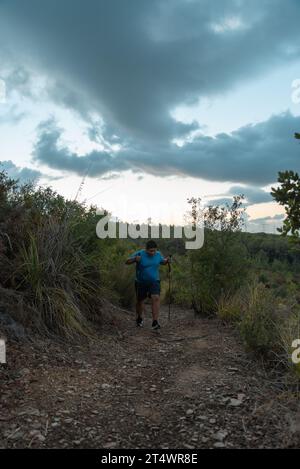 Les hommes en surpoids s'entraînent dans les montagnes soutenus par des bâtons de sport. Banque D'Images