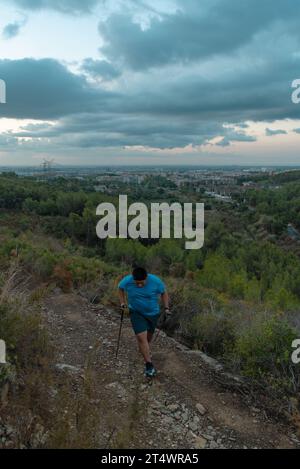 Les hommes en surpoids s'entraînent dans les montagnes soutenus par des bâtons de sport. Banque D'Images