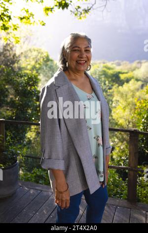 Heureuse femme senior biracial debout et souriant dans le jardin ensoleillé, espace de copie Banque D'Images