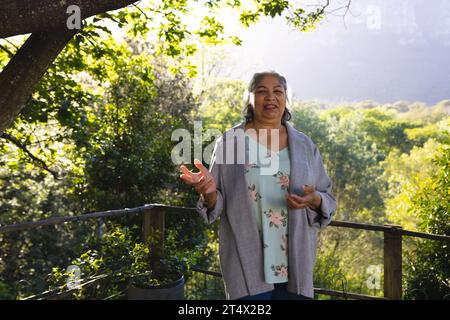 Heureuse femme senior biracial debout et parlant dans le jardin ensoleillé, espace de copie Banque D'Images