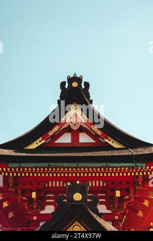 Un bâtiment chinois rouge richement détaillé se dresse sur un ciel bleu vif, avec ses caractéristiques architecturales vibrantes qui se démarquent sur le fond Banque D'Images