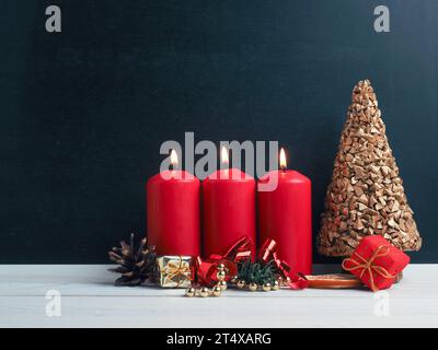 Bougies du troisième Avent brûlant avec décoration de Noël sur un tableau noir, saisonnier ou de vacances Banque D'Images