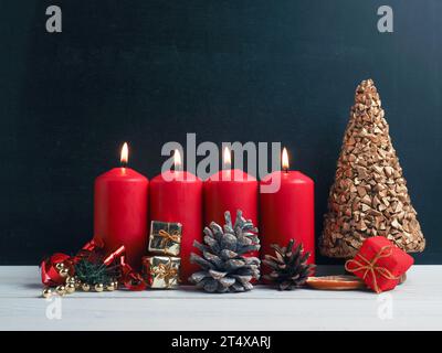 Bougies du quatrième Avent brûlant avec décoration de Noël sur un tableau noir, saisonnier ou de vacances Banque D'Images