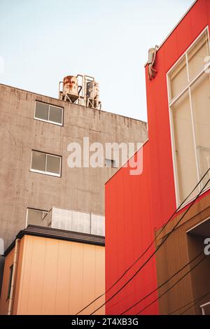 Un paysage urbain vibrant avec un groupe de bâtiments rouges et orange lumineux au premier plan, avec un bâtiment plus grand en arrière-plan Banque D'Images