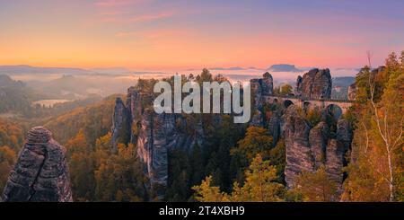 Une large photo panoramique de 2:1 d'un lever de soleil d'automne avec vue depuis le Ferdinandstein avec beaucoup de couleurs d'automne au pont Bastei, une partie du Baste Banque D'Images