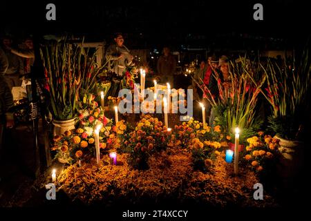 02 novembre 2023, Mexique, Ciudad de México : une famille décore la tombe d'un de leurs proches avec des fleurs et des bougies au cimetière de Tlahuac. Beaucoup de gens ont visité les différents cimetières de Mexico pour commémorer leurs proches décédés dans le cadre des célébrations du jour des morts. Photo : Jair Cabrera Torres/dpa Banque D'Images