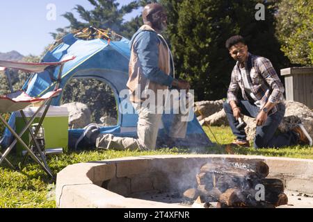 Heureux père afro-américain et fils adulte lançant tente prenant un repos au soleil, espace de copie Banque D'Images