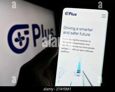 Personne tenant un téléphone cellulaire avec la page Web de la société de camionnage autonome américaine PlusAI Inc. Devant le logo de l'entreprise. Concentrez-vous sur le centre de l'écran du téléphone. Banque D'Images