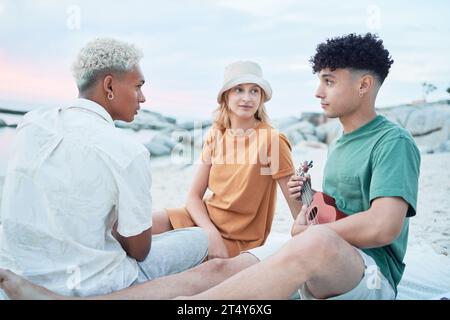 Guitare, plage et amis en vacances à la mer en Espagne avec la musique d'un musicien pour la paix et le calme dans la nature. Les personnes qui écoutent le son de Banque D'Images