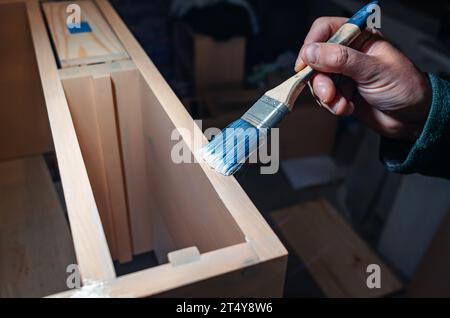 Le pinceau applique du vernis sur les meubles. Vernissage de meubles avec vernis Banque D'Images