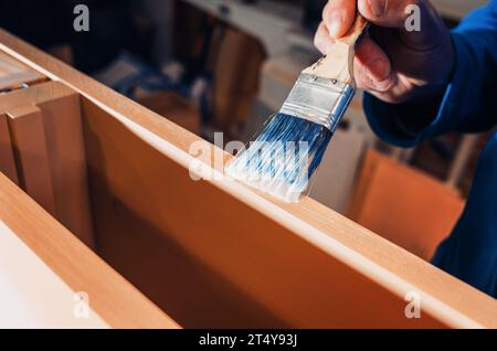 Le pinceau applique du vernis sur les meubles. Vernissage de meubles avec vernis Banque D'Images