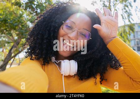 portrait d'une belle jeune femme afro-américaine heureuse souriante regardant la caméra prendre un selfie en plein air. Banque D'Images