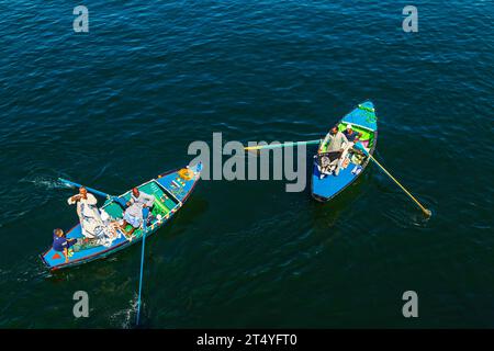 Les vendeurs de textiles sur leurs bateaux approchent un bateau de croisière en attendant d'entrer dans l'écluse d'Esna. Les vendeurs espèrent vendre des marchandises aux touristes. Esna, Égypte – octobre 20 Banque D'Images