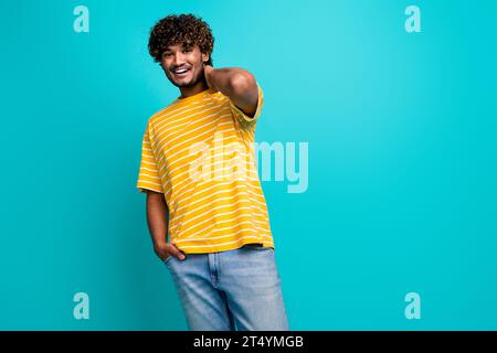 Photo portrait de joli jeune mâle toucher cou posant modèle porter vêtement jaune rayé tendance isolé sur fond de couleur aigue-marine Banque D'Images