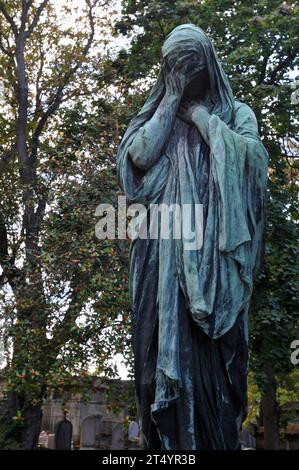 Sculpture d'un personnage camouflé sur une tombe du cimetière historique du Père Lachaise à Paris. Banque D'Images