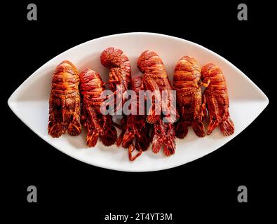 Homards européens bouillis (Scyllarus arctus) sur une assiette sur fond noir - fruits de mer de grande valeur du nord de l'Espagne communément appelés 'santi Banque D'Images