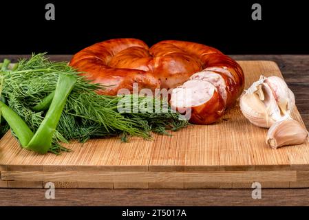 Saucisse frite maison en tranches sur une planche à découper en bois et ail aux herbes. Nourriture maison. Banque D'Images