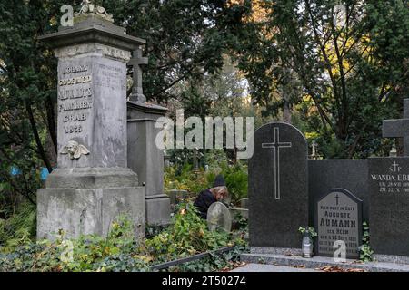 Une femme est assise près de la tombe le jour de la Toussaint au cimetière évangélique d'Augsbourg à Varsovie. La Toussaint (ou Dzie ? Zaduszny en polonais) est un jour férié en Pologne. C’est l’occasion de se souvenir de parents décédés. Ce jour-là, les gens apportent des fleurs, généralement des chrysanthèmes, et des bougies aux cimetières. Tout le cimetière est rempli de lumières dans l'obscurité. Le cimetière évangélique d'Augsbourg est un cimetière protestant luthérien historique situé dans la partie ouest de Varsovie. Depuis son ouverture en 1792, plus de 100 000 personnes y ont été enterrées. Banque D'Images