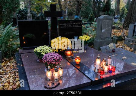 Des bougies sont placées sur la tombe sans nom le jour de la Toussaint au cimetière évangélique d'Augsbourg à Varsovie. La Toussaint (ou Dzie ? Zaduszny en polonais) est un jour férié en Pologne. C’est l’occasion de se souvenir de parents décédés. Ce jour-là, les gens apportent des fleurs, généralement des chrysanthèmes, et des bougies aux cimetières. Tout le cimetière est rempli de lumières dans l'obscurité. Le cimetière évangélique d'Augsbourg est un cimetière protestant luthérien historique situé dans la partie ouest de Varsovie. Depuis son ouverture en 1792, plus de 100 000 personnes y ont été enterrées. Banque D'Images