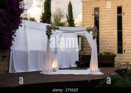 Un chuppah ou canopée de tissu de dentelle blanche est préparé pour une cérémonie de mariage juif. Banque D'Images