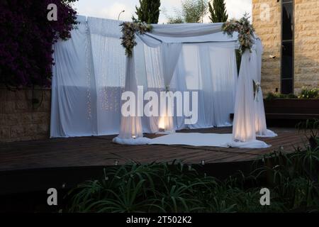 Un chuppah ou canopée de tissu de dentelle blanche est préparé pour une cérémonie de mariage juif. Banque D'Images