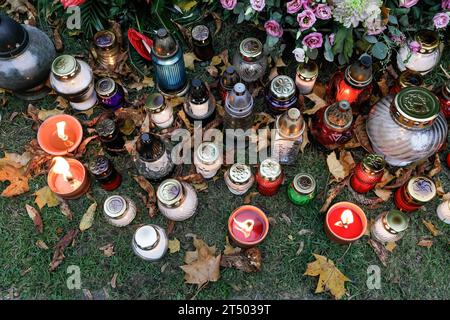 Des bougies et des lanternes sont placées près de la tombe le jour de la Toussaint au cimetière évangélique d'Augsbourg à Varsovie. La Toussaint (ou Dzie ? Zaduszny en polonais) est un jour férié en Pologne. C’est l’occasion de se souvenir de parents décédés. Ce jour-là, les gens apportent des fleurs, généralement des chrysanthèmes, et des bougies aux cimetières. Tout le cimetière est rempli de lumières dans l'obscurité. Le cimetière évangélique d'Augsbourg est un cimetière protestant luthérien historique situé dans la partie ouest de Varsovie. Depuis son ouverture en 1792, plus de 100 000 personnes y ont été enterrées. (Photo de Volha S. Banque D'Images