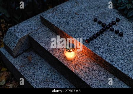 Varsovie, Pologne. 1 novembre 2023. Une bougie et une croix en châtaignes sont placées sur la tombe le jour de la Toussaint au cimetière évangélique d'Augsbourg à Varsovie. La Toussaint (ou Dzie ? Zaduszny en polonais) est un jour férié en Pologne. C’est l’occasion de se souvenir de parents décédés. Ce jour-là, les gens apportent des fleurs, généralement des chrysanthèmes, et des bougies aux cimetières. Tout le cimetière est rempli de lumières dans l'obscurité. Le cimetière évangélique d'Augsbourg est un cimetière protestant luthérien historique situé dans la partie ouest de Varsovie. Depuis son ouverture en 1792, plus de 100, 0 Banque D'Images