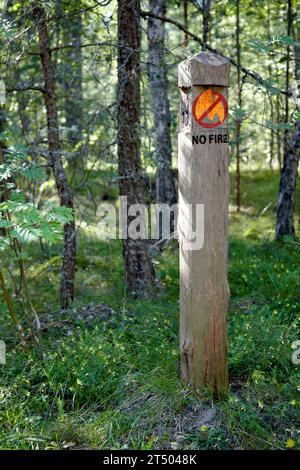 Poteau d'information en bois dans la forêt d'été avec une interdiction de faire des feux. Banque D'Images