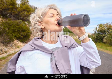 Femme âgée, eau potable et bouteille sur la route pour le fitness, la course ou la pensée pour la vision, l'hydratation ou la santé. Dame mature, coureuse et détox avec Banque D'Images