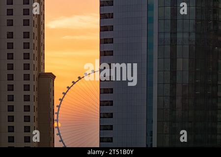 Dubaï, Émirats arabes Unis- 21 septembre 2023 : la silhouette stationnaire d'Ain Dubaï entre des blocs de tours résidentiels au Dubai Marine, une image de coucher de soleil. Banque D'Images