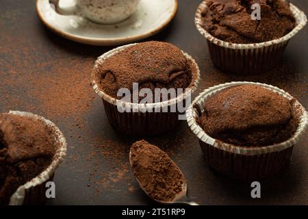 Muffins bruns au chocolat et au cacao avec cappuccino café dans la vue d'angle de tasse sur fond de pierre rustique brun, cupcakes doux au chocolat noir maison Banque D'Images