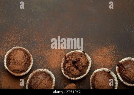 Muffins bruns au chocolat et cacao en cuillère à café vue de dessus sur fond de pierre rustique brun, cupcakes doux au chocolat noir faits maison Banque D'Images