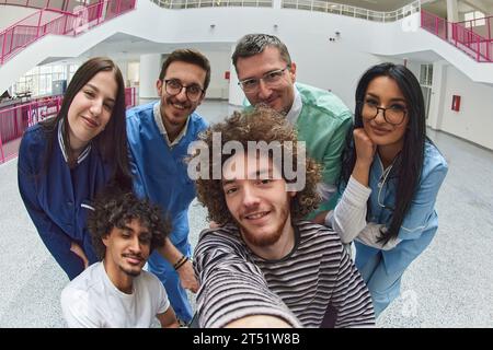 Une équipe d’experts médicaux et de médecins capte un moment joyeux, prenant un selfie avec un patient en fauteuil roulant, symbolisant l’inclusivité, le soutien, et Banque D'Images