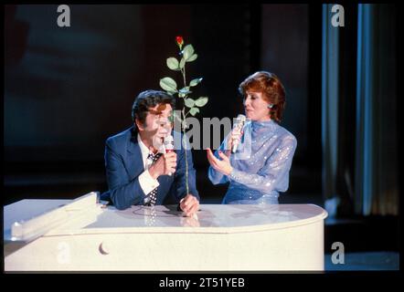 Monsieur 100,000 Volt 1982 : ICH SAGS Dir durch die Blume Fotos : Leopold NEKULA/VIENNAREPORT e. U. âÖï ORF Caterina Valente-TV-Show Caterina xx. Mai 1982, Stadthalle, Wien . âžï https://www.palaismontcalm.ca/concert-spectacle-quebec/et-maintenant-le-spectacle-hommage-a-gilles-becaud-13-avril-2024/ . Bild : Gilbert Becaud singt mit einer roten Rose in der Hand zusammen mit Caterina Valente auf der Bühne der Wiener Stadthalle. Gilbert BÃ caud * 24. Oktober 1927 als Francois Gilbert LÃ Opold Silly in Toulon, Frankreich 18. Dezember 2001 in Paris 1 war ein französischer chansonnier. Er wurde wege Banque D'Images