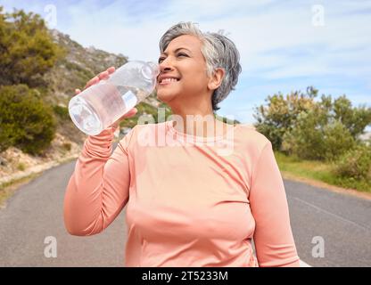 Femme âgée, eau potable et bouteille sur la route pour le fitness, la course et la pensée de but, hydratation ou santé. Dame mature, coureuse et détox avec Banque D'Images