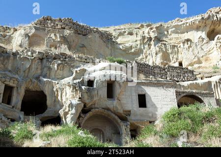 La vue sur les vieilles maisons du village Cavusin sculptées à l'intérieur de roche tendre dans la région de Cappadoce (Turquie). Banque D'Images