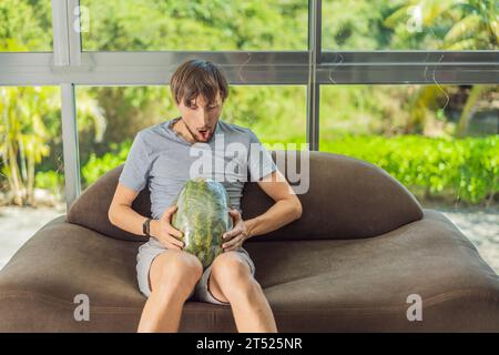 Une image humoristique : une femme enceinte et son mari utilisent de manière ludique une pastèque à la place d'un ventre, mettant en évidence de manière comique les défis de la navigation Banque D'Images