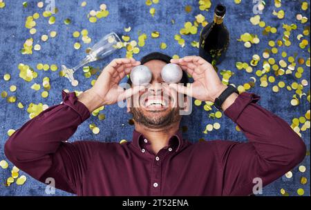 Noël, ivre et drôle avec un homme sur le sol, riant lors d'une fête ou d'un événement de célébration d'en haut. Comique, comédie ou festive avec un heureux Banque D'Images