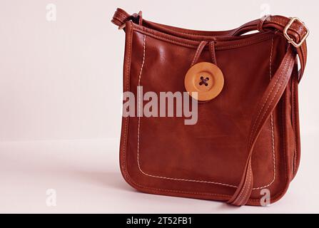 Sac à main en cuir brun foncé pour femme avec bandoulière sur fond blanc. Banque D'Images