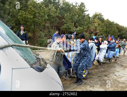 1103192653B-047 MISAWA, Japon (le 19 mars 2011) des membres du Service et des résidents de Misawa tirent un véhicule endommagé des bois près du port de Misawa. Les membres du service, les employés civils et les membres de la famille de la Naval Air Facility Misawa aident les résidents à nettoyer le port à la suite d'un tremblement de terre de magnitude 9,0 qui a causé un tsunami dévastateur le long de la côte est du Japon. Marine Banque D'Images