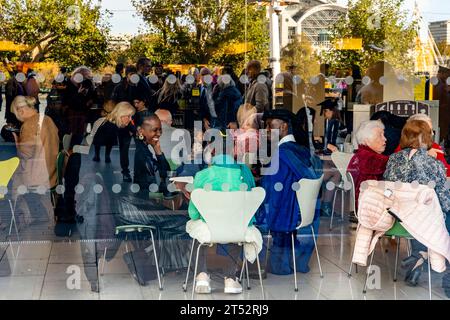 Un étudiant en costume traditionnel assis dans Un café à sa cérémonie de remise des diplômes, The Southbank, Londres, Royaume-Uni. Banque D'Images