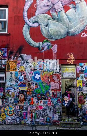 Une jeune femme sortant les ordures dans Une propriété colorée de Brick Lane, Londres, Royaume-Uni Banque D'Images