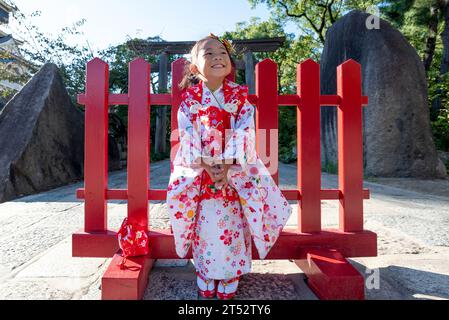 Une jeune fille heureuse portant un kimono japonais rouge Banque D'Images