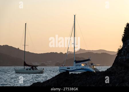 Tranquillité côtière : rêve coucher de soleil flou sur la côte de Russell avec des bateaux, Bay of Islands, Nouvelle-Zélande Banque D'Images