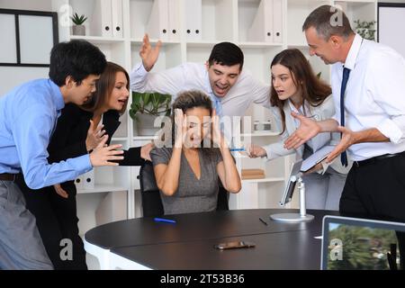 Femme d'affaires mature souffrant de collègues bruyants dans le bureau Banque D'Images