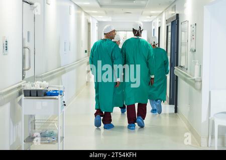 Divers chirurgiens masculins et féminins portant des blouses chirurgicales marchant dans le couloir à l'hôpital Banque D'Images