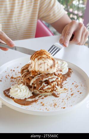 Homme ayant des crêpes avec de la crème glacée dans un café restaurant, café. Banque D'Images