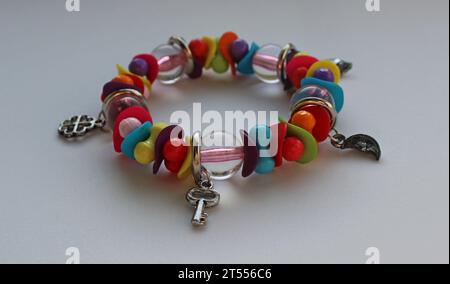 Perles multicolores et breloques en argent dans un bracelet de poignet isolé sur vue d'angle blanc Banque D'Images