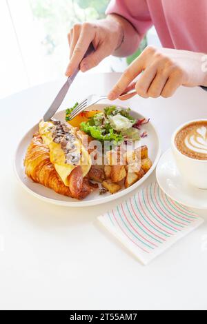 Sandwich brioche aux œufs croissants et saucisses avec fruits et légumes frais dans un café. Banque D'Images